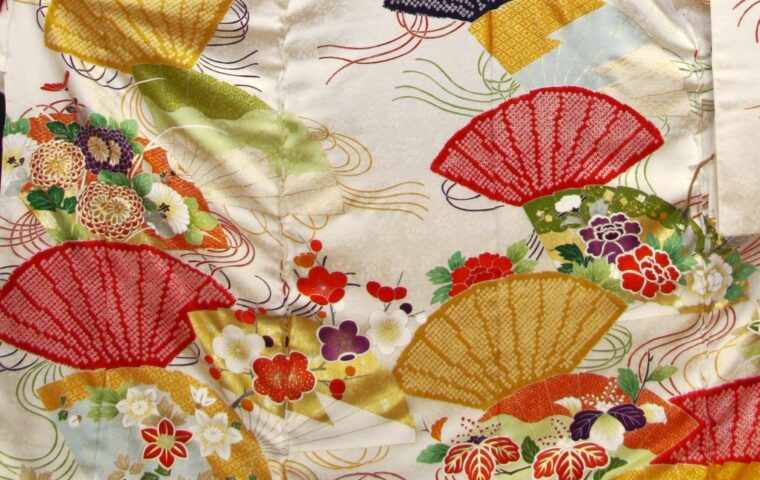 白地に色とりどりの扇面と菊・梅・牡丹が舞う振袖の柄アップ