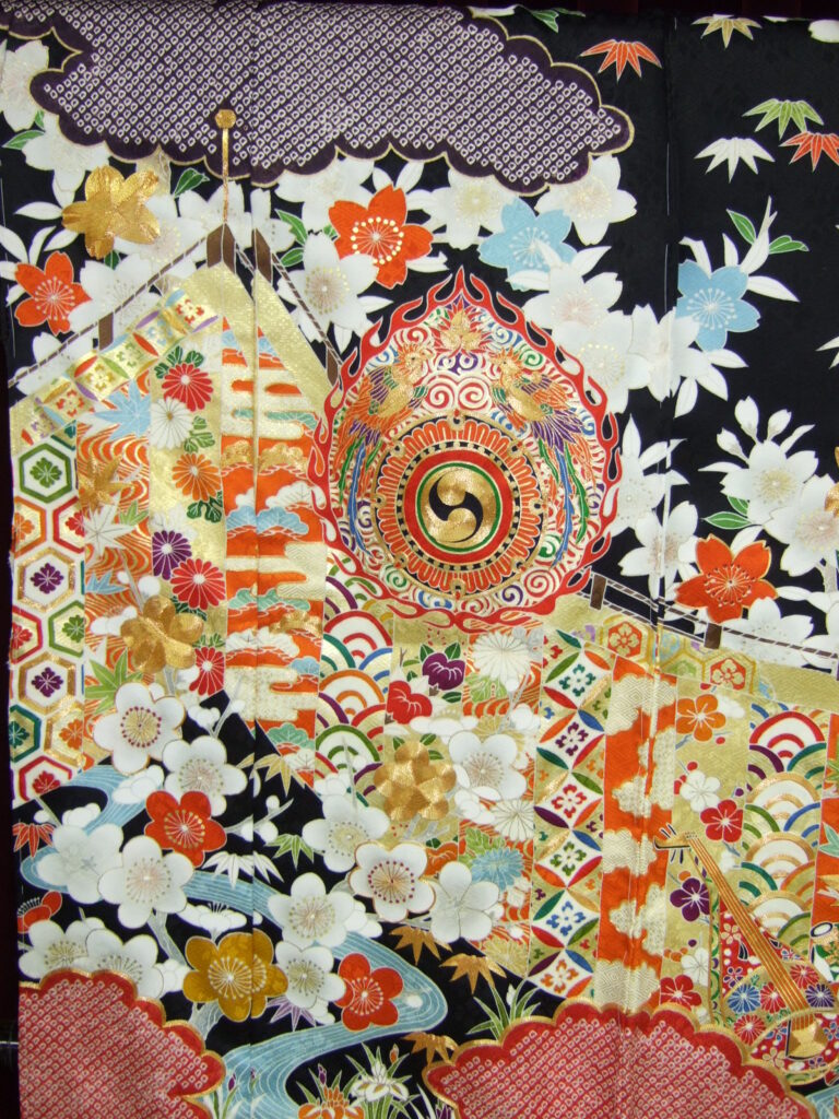黒地に火焔太鼓・桜・梅・琴など王朝吉祥文様を金彩で密に配した黒振袖の柄アップ