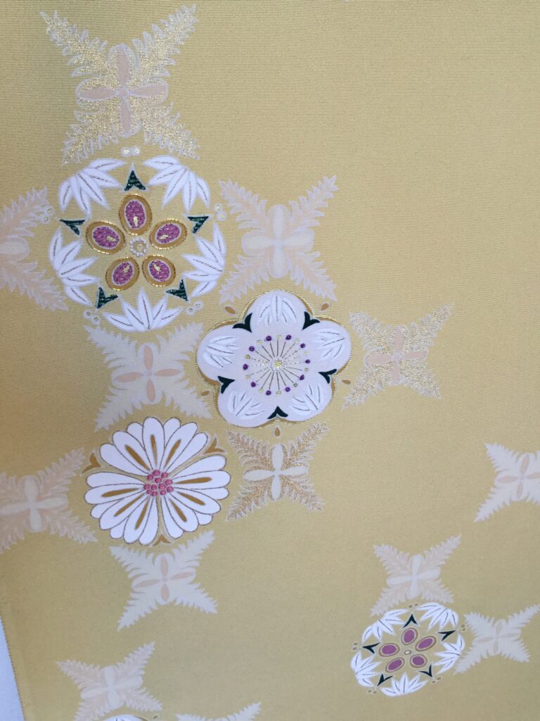 山吹色地に白刺繍の菊・梅・花丸文様が散りばめられた着物生地アップ｜染と呉服はっとり
